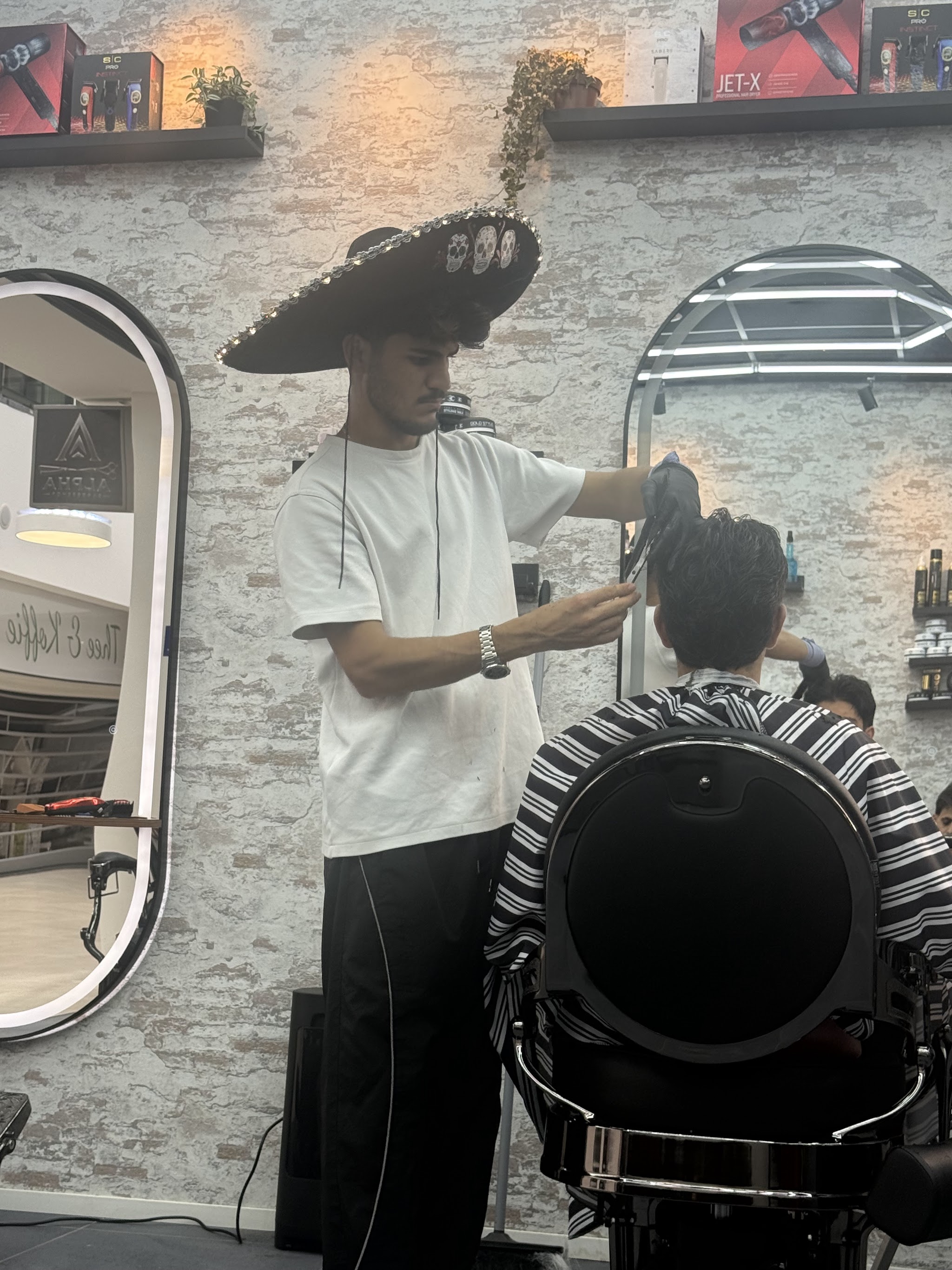 Barber aan het werk bij de spiegelwand van Alpha Hairstyling